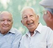 An older man laughing and speaking with his friends