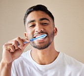 Man smiling while brushing his teeth