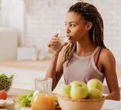 Woman drinking water while preparing fruits and vegetables