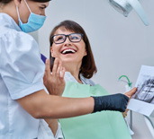 Woman smiling with dentist while reviewing X-ray
