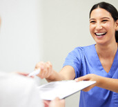 dental assistant smiling while handing patient form